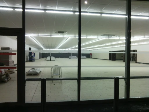 Nouvel espace de vente Intérieur vide d'un magasin avec des néons et des étagères inoccupées.