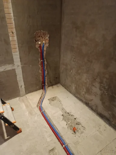 Pendant, douche Tuyaux de plomberie colorés attachés à un mur en béton dans une pièce inachevée.