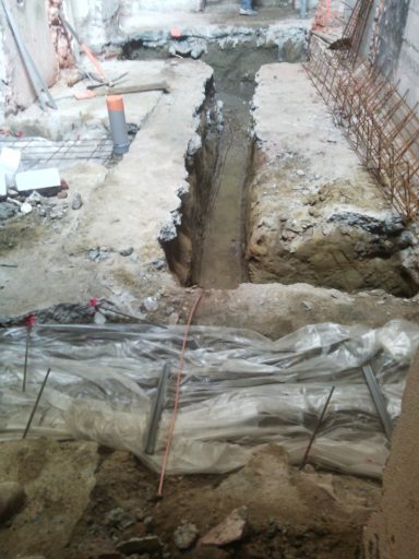 Tranchées réseaux Tranchée pour des travaux de construction, avec béton et armatures visibles.