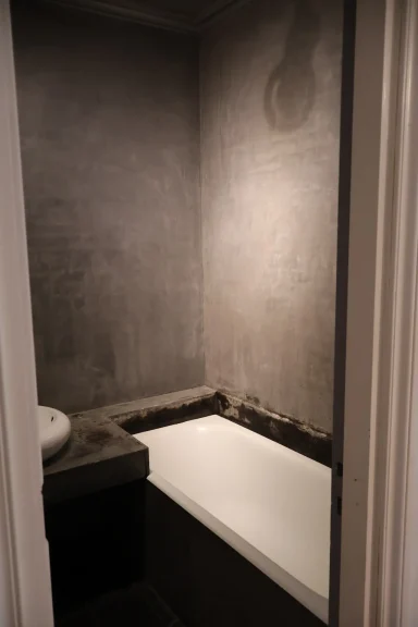 Avant, baignoire Salle de bain avec murs en béton et baignoire blanche.