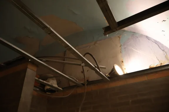 Avant, plafond Plafond avec conduites et éclairage, présentant des signes d'usure et de peinture écaillée.